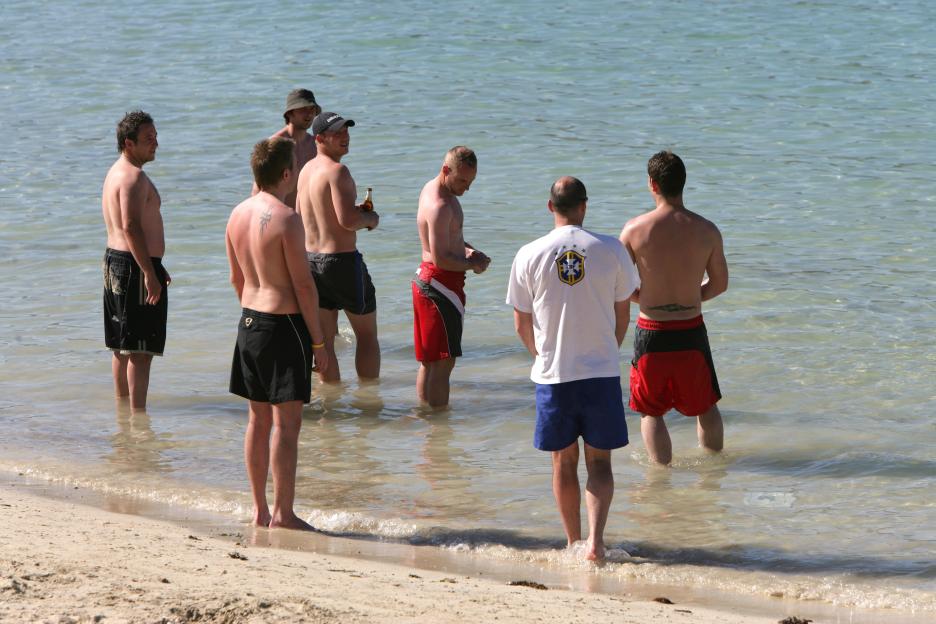Group of men on a beach in the shallow water.