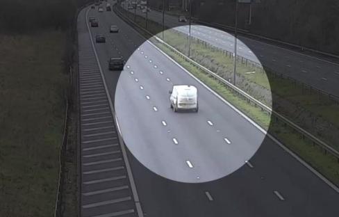 White van driving on a highway.