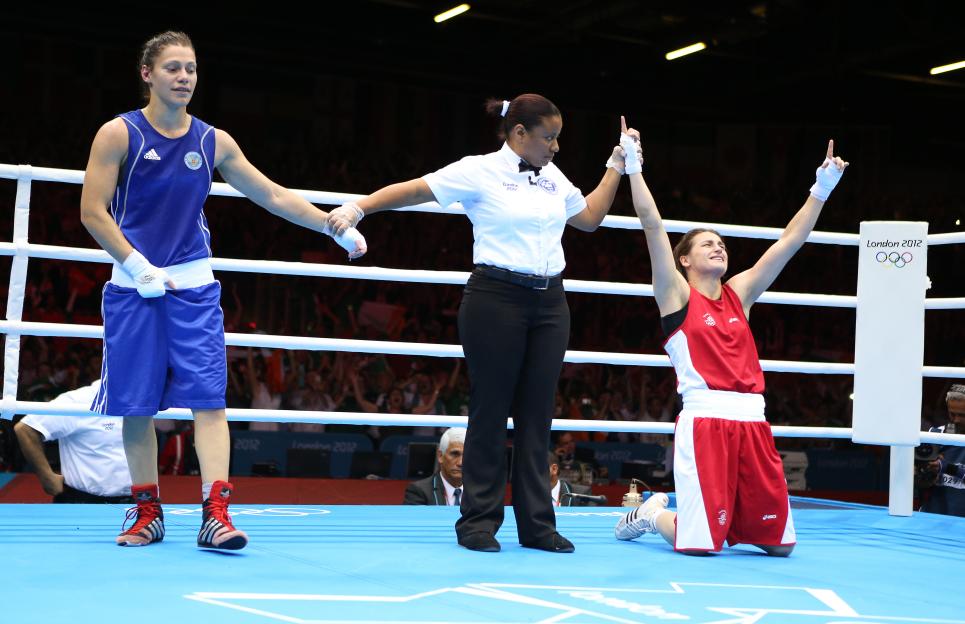 Katie Taylor, in red boxing gear, celebrates her Olympic boxing win.