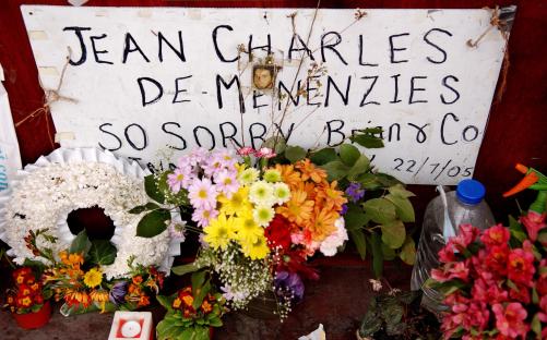Memorial to Jean Charles de Menezes with flowers and a handwritten sign.