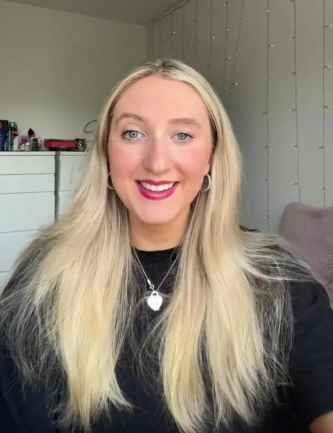 Woman with long blonde hair wearing a black shirt and necklace.