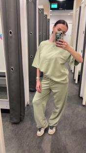 Woman in a sage green tracksuit in a Primark changing room.