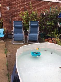 Paddling pool in a garden with two lounge chairs.