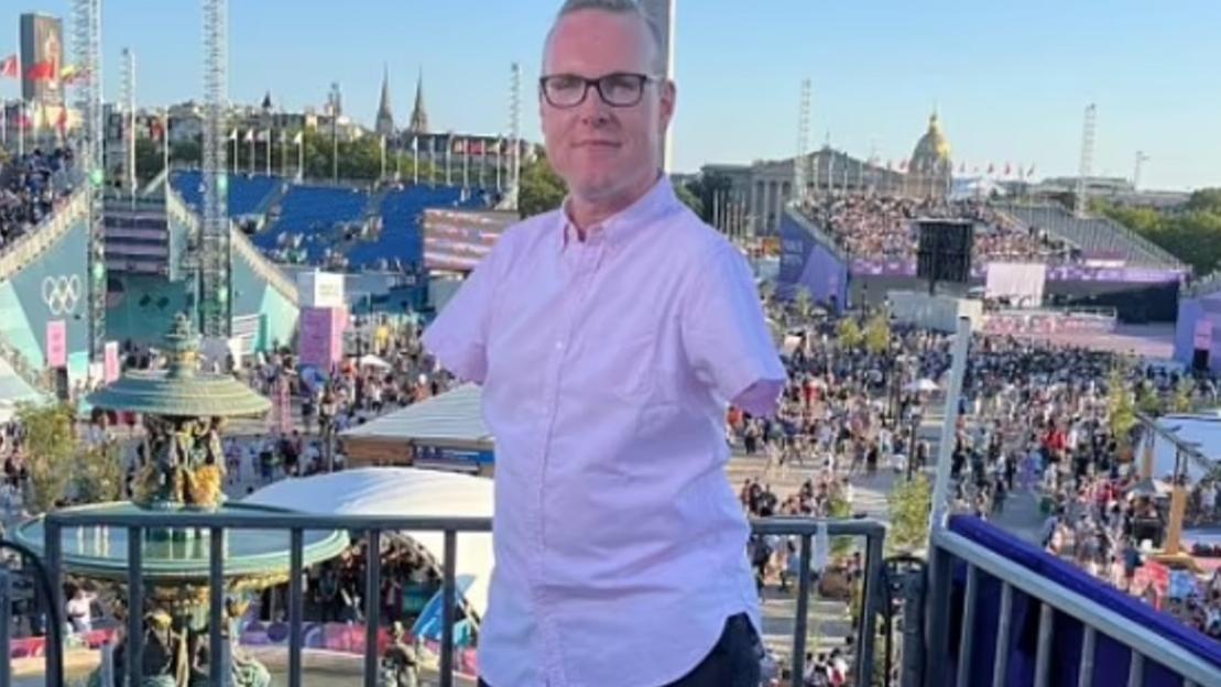 Man with short sleeves and glasses at an outdoor event.