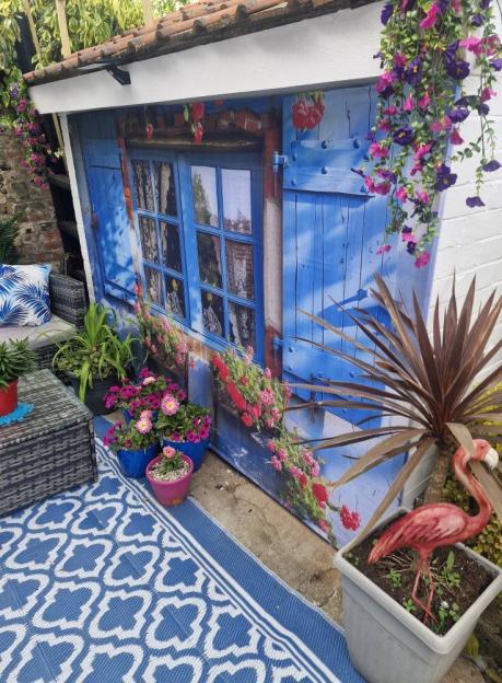 Garden with a mural of a blue building and flowers.