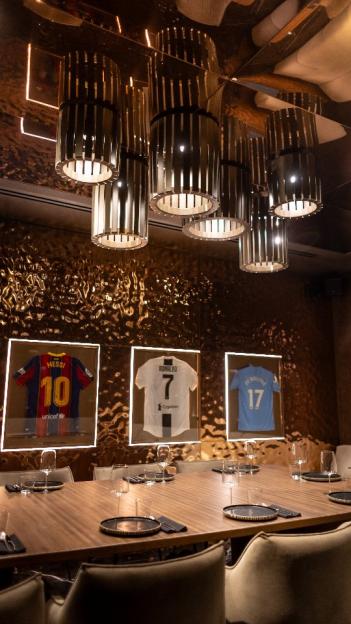 Interior of INCH Restaurant, featuring framed soccer jerseys and a long dining table.