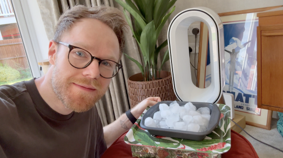 A man placing ice cubes in front of a fan.