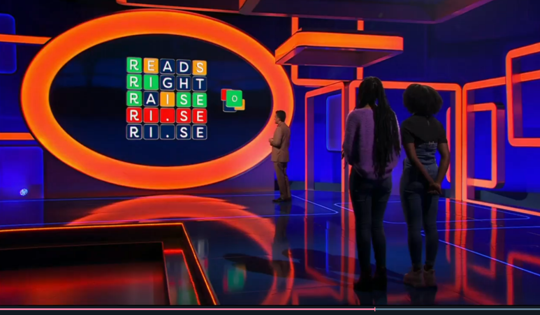 Game show set with contestants and a word puzzle.