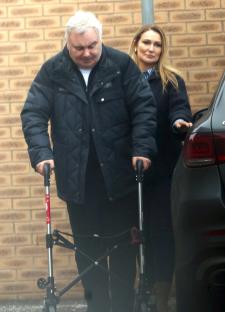 Eamon Holmes using a walker, assisted by Kate Alexandra.