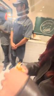 A McDonald's employee stands with hands clasped while a customer holds food.