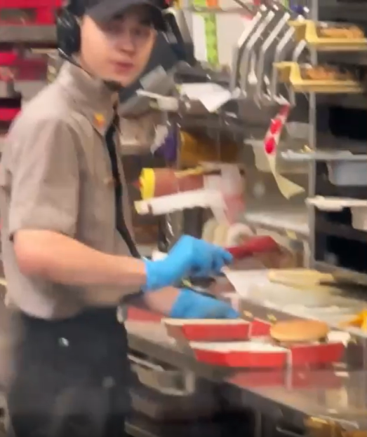 Fast food worker assembling burgers.