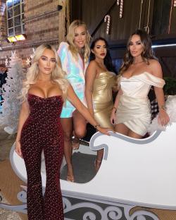 Four women in party attire posing on a sleigh.
