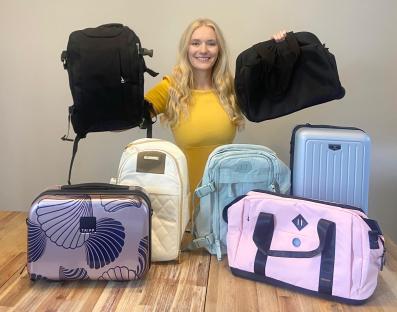 Woman holding various bags and luggage.