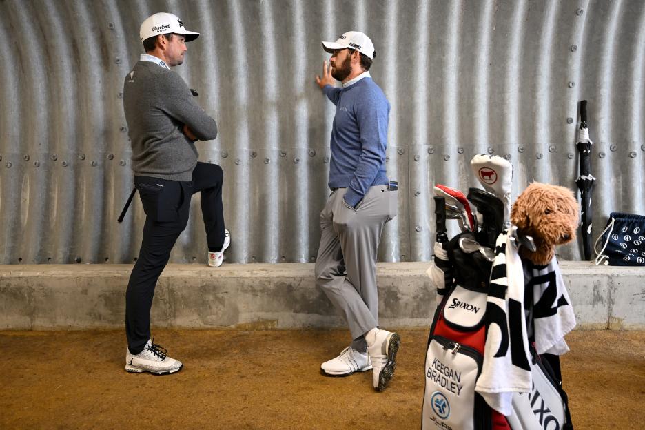Keegan Bradley and Patrick Cantlay sheltering in a tunnel during a golf tournament.
