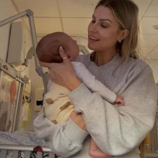Woman holding a newborn baby in a hospital.
