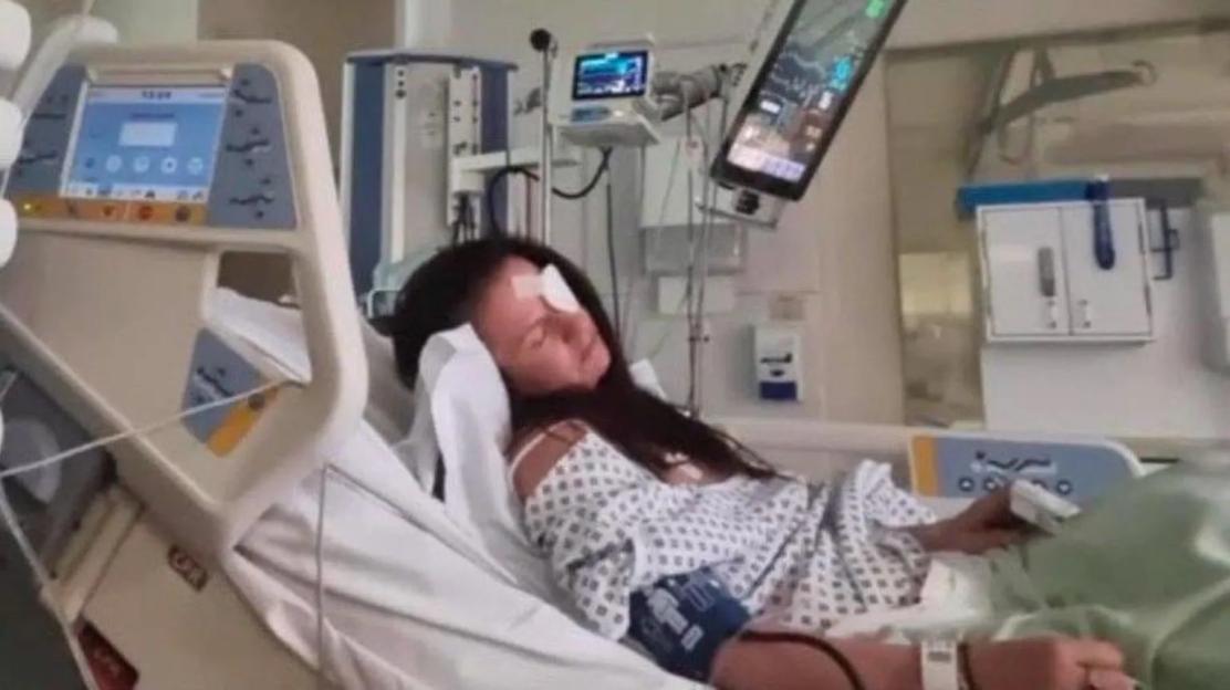 Woman in hospital bed with eye patch.