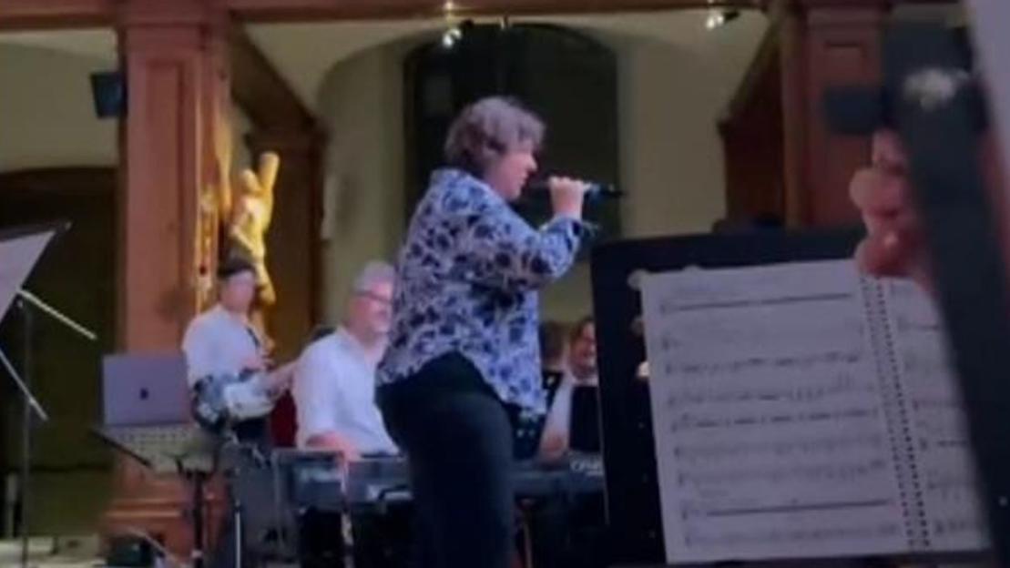 A woman singing into a microphone during a performance.