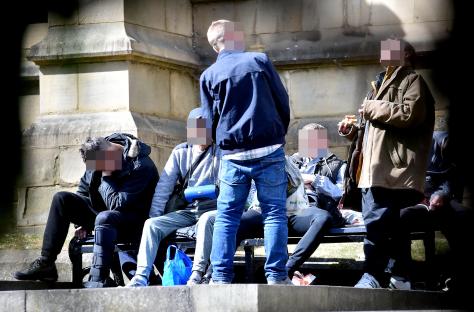 Group of people sitting on a bench near a cathedral.