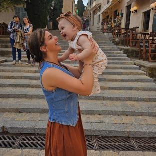 Woman holding up her baby daughter on stone steps.