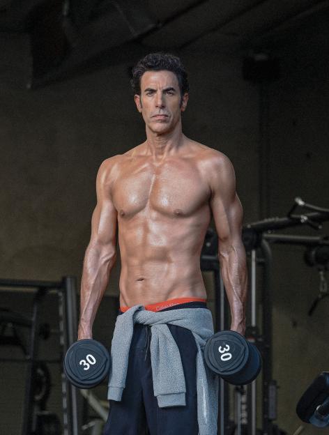 Sacha Baron Cohen holding 30-pound dumbbells.