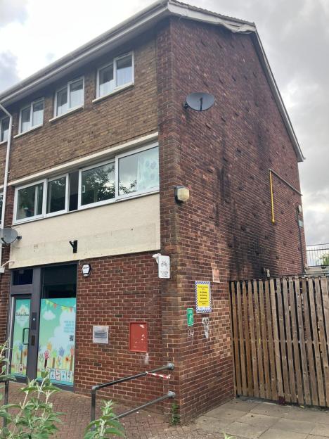 Fire-damaged brick building with a daycare sign.