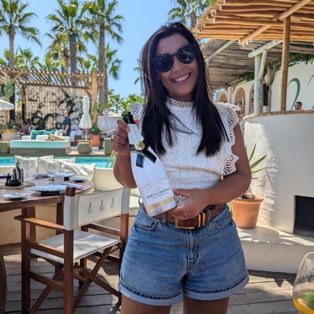 Woman holding a bottle of Moët & Chandon Ice Impérial champagne at an outdoor restaurant.