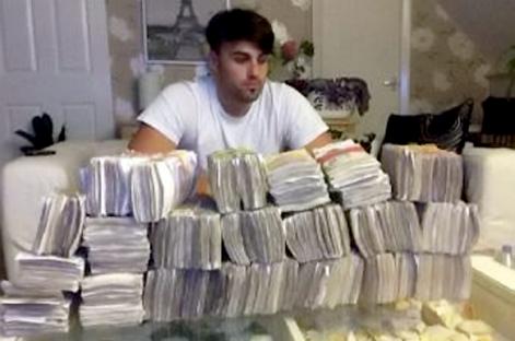 Man sitting behind large stacks of cash.