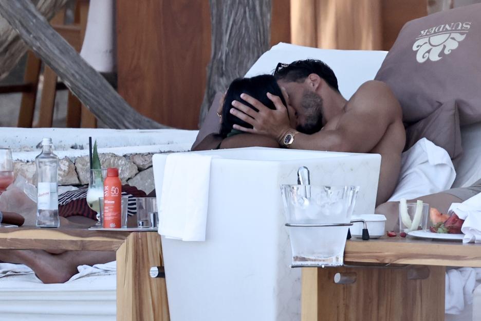 Maya Jama and Ruben Dias kissing on a beach lounger.