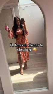 Woman in orange and white striped outfit taking a selfie in a mirror.