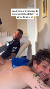 Man receiving a massage while another man playfully teases him.