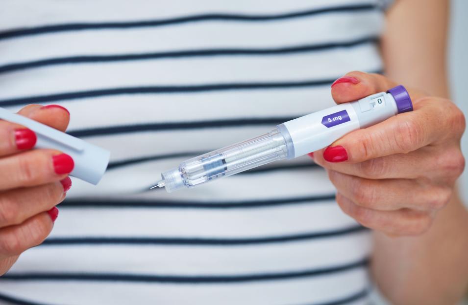 Woman holding a 5 mg injection pen.