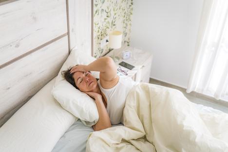 Woman lying in bed with a headache.