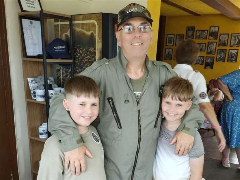 A grandfather in a flight suit with his two grandsons.