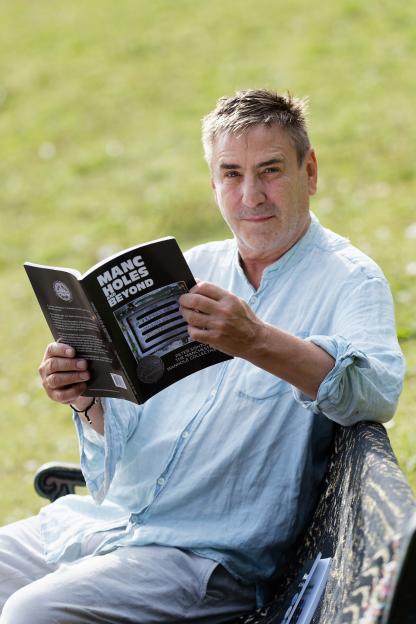 Man reading his book, *Manc Holes and Beyond*.