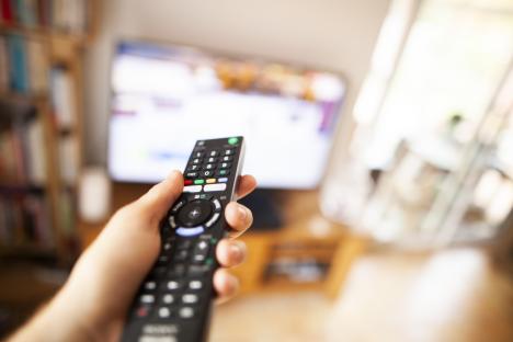 Person using a remote control to change television channels.