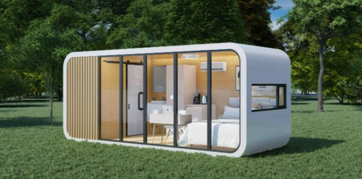 Illustration of a small, modern, white cabin in a grassy field.