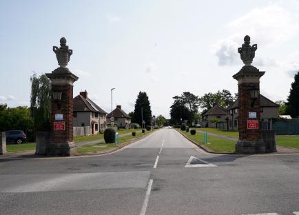 Residential street with ornate brick pillars at the entrance.