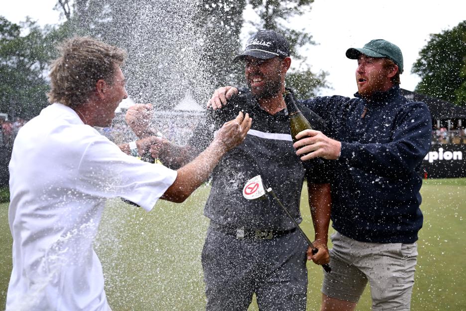 A golfer celebrates his win with friends, being sprayed with champagne.