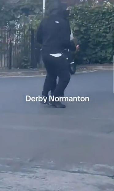 Person in dark clothing walking down a street in Derby Normanton.