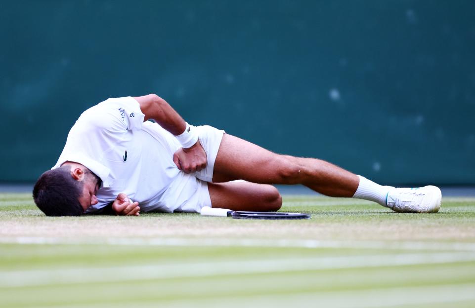 Novak Djokovic lying on the court after losing a match point.