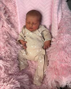 Sleeping newborn baby on pink blanket.