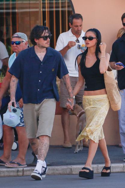 Brooklyn Beckham and Nicola Peltz holding hands while walking.