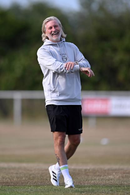 Robbie Savage, manager of Forest Green Rovers, smiling on a soccer field.