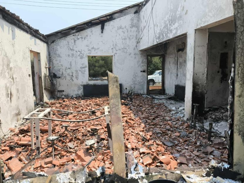 The interior of a fire-damaged home, showing broken tiles and debris on the floor.