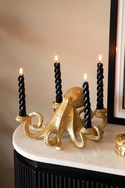 Gold octopus candlestick holder with four black candles.