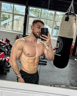 A muscular man taking a selfie in a gym.