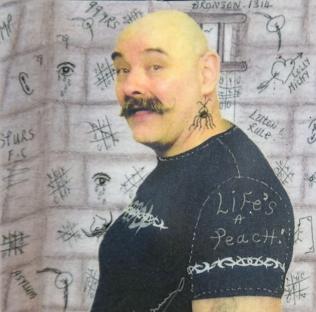 Portrait of Charles Bronson, British criminal, against a wall covered in graffiti.
