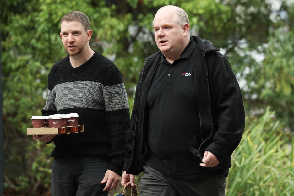 Two men carrying coffee outside a courthouse.