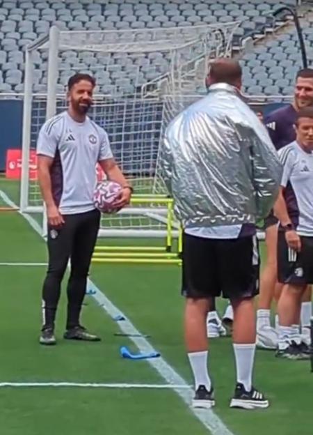 Soccer coach holding a ball during a practice session.