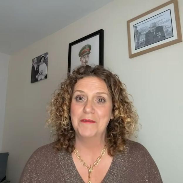 Hannah Ingram-Moore in a video, speaking to the camera. Framed photos of family members are on the wall behind her.